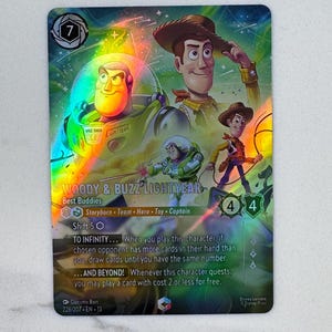 Könnte beinhalten: Eine holografische Disney Lorcana Sammelkarte mit Woody und Buzz Lightyear. Die Karte zeigt den Titel Woody & Buzz Lightyear, Best Buddies, zusammen mit Spielstatistiken, Fähigkeitstexten und Charakterillustrationen vor einem farbenfrohen Weltraumhintergrund.