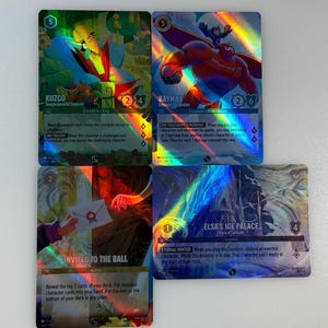 May include: Four holographic trading cards featuring characters from Disney animated films. The cards are from the Disney Lorcana trading card game. The characters featured are Kuzco from The Emperor's New Groove, Baymax from Big Hero 6, Elsa from Frozen, and a character from the movie Enchanted. The cards have a rainbow holographic effect.