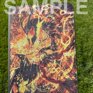 Puede incluir: Una funda rectangular para tableta con un estampado gráfico vibrante de una criatura oscura y blindada rodeada de llamas naranjas y amarillas y patrones circulares brillantes. La palabra SAMPLE está impresa en letras blancas semitransparentes.
