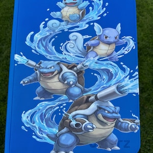 May include: A bright blue rectangular tablet case featuring a graphic illustration of the evolution of the water-type creature Squirtle, Wartortle, and Blastoise. The characters are depicted in a dynamic sequence surrounded by swirling water effects.