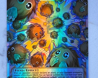 May include: A holographic trading card featuring the text "Multiplying Kuriboh!" and various cartoonish creatures. The card has a dark background with a colorful design and the text "FIEND/EFFECT". The card's ATK is 300 and DEF is 200.