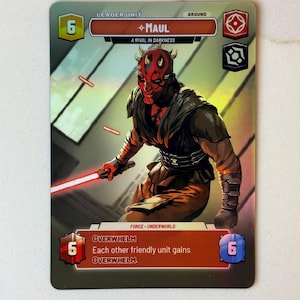 May include: A Star Wars collectible card featuring Darth Maul, a red and black Sith Lord with horns. The card is a leader unit with a power of 6 and the text "A Rival in Darkness".