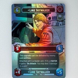 Puede incluir: Una carta de juego de cartas coleccionables con Luke Skywalker de Star Wars. La carta es holográfica y presenta una imagen colorida de Luke Skywalker en la cabina de su X-Wing. El texto de la carta dice: "Leader Unit, Ground, 6, ◇Luke Skywalker, Hero of Yavin, 5, This upgrade can't be defeated by enemy card abilities. Attached unit is a leader unit. If it's a FIGHTER, it gains: "On Attack: You may deal 3 damage to a unit." +4, ◆Luke Skywalker, Force Rebel Pilot, 6, +5"