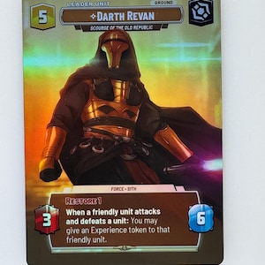 Może przedstawiać: Holograficzna karta kolekcjonerska z Darthem Revanem z uniwersum Gwiezdnych Wojen. Karta ma złotą i czarną kolorystykę, a postać jest przedstawiona w czarnym płaszczu i złotej zbroi. Tekst na karcie zawiera "Leader Unit" i "Restore 1".