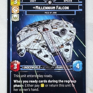 Puede incluir: Una tarjeta coleccionable con el Halcón Milenario, una nave espacial de Star Wars. La tarjeta tiene un fondo azul oscuro con el texto "Millennium Falcon" y "Piece of Junk". La tarjeta también incluye instrucciones del juego y un número de unidad.