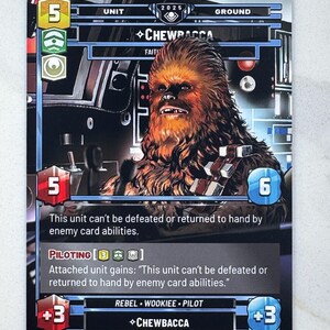 May include: A Star Wars trading card featuring Chewbacca. The card has a portrait of Chewbacca, with text including "Chewbacca", "Rebel", and game statistics. The card is predominantly black, with blue, red, and yellow accents.
