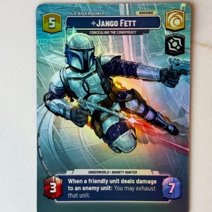 Puede incluir: Una carta de juego de cartas coleccionables de Star Wars: The Mandalorian con Jango Fett, un cazarrecompensas. La carta es azul y blanca con una imagen de Jango Fett con su armadura mandaloriana. El texto de la carta dice "Leader Unit, Ground, 5, ◇Jango Fett, Concealing the Conspiracy, Underworld - Bounty Hunter, 3, When a friendly unit deals damage to an enemy unit: You may exhaust that unit, 7".