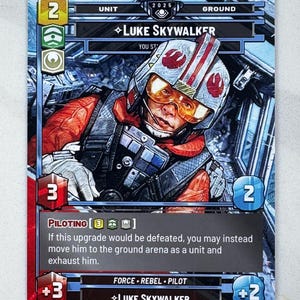 May include: A trading card featuring Luke Skywalker in a pilot's helmet and orange flight suit. The card has a red border and includes text such as "PILOTING" and "FORCE REBEL PILOT". The card is numbered 89.