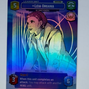 May include: A blue and silver card game card featuring Leia Organa, a character from Star Wars. The card has a holographic effect and features the text "LEADER UNIT", "LEIA ORGANA", "ALLIANCE GENERAL", "REBEL OFFICIAL", "GROUND", "RAID 1", "When this unit completes an attack: You may attack with another REBEL unit."