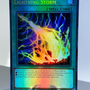 May include: A holographic trading card for the game Yu-Gi-Oh! featuring a lightning bolt striking the ground. The card is blue and green with a holographic effect. The card text reads "Lightning Storm" and "[SPELL CARD]".