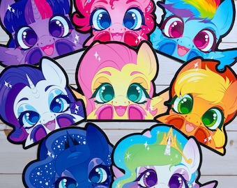 May include: A collection of colorful cartoon pony face cutouts. Each pony has large eyes, a unique color scheme, and a smiling expression. The ponies include pink, blue, purple, yellow, and orange characters with various hair colors and styles.