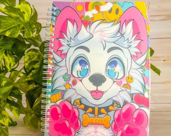 May include: A spiral-bound notebook featuring a cartoon dog with large blue eyes, pink ears, and paws. The dog has a bone-shaped tag that says "STICKERS". The background is a colorful mix of smiley faces, rainbows, and strawberries.