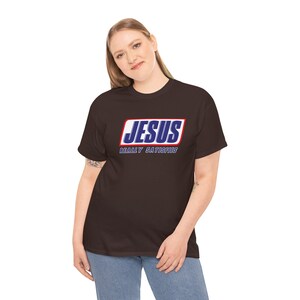 May include: A brown t-shirt with a white and blue graphic that says "JESUS REALLY SATISFIES" in a style similar to the Snickers logo.
