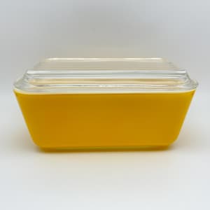 May include: A yellow glass storage container with a clear glass lid. The lid has a ribbed design.