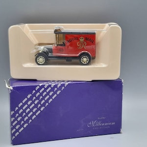 Puede incluir: Una furgoneta de reparto roja de Royal Mail con un chasis negro y un techo blanco. La furgoneta tiene un logotipo de Royal Mail en blanco y negro en el lateral. La furgoneta está en una vitrina de plástico transparente con una caja morada debajo. La caja tiene las palabras "Royal Mail Millennium Collection" impresas en ella.