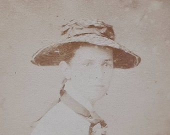 May include: A black and white vintage photograph of a person wearing a wide-brimmed hat. The person is looking to the right of the frame.