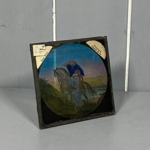 May include: A vintage glass slide depicting a man on horseback, with a second man riding behind him. The slide is framed in black and has a label that reads "Perkins & Co.  Danville, Va."