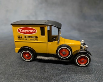 May include: A yellow vintage toy delivery truck with black fenders and a black roof. The truck has red wheels with white tires. The side of the truck has the text "Taystee Old Fashioned Enriched Bread".