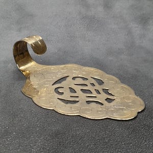 Pode incluir: Um servidor de torta dourado e ornamentado com uma alça curva. O servidor tem um design decorativo vazado na lâmina. A lâmina tem aproximadamente 15 cm de comprimento.