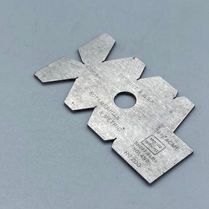 May include: A silver metal thread gauge with markings for 55° Whit & BSF, 14½ ACME, and 60° American & Metric threads. The gauge is labelled "Moore & Wright Sheffield England No. 200".