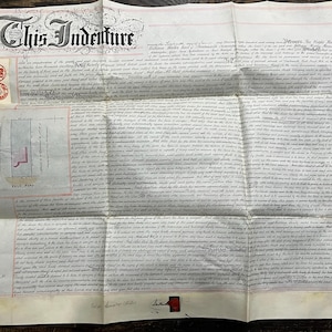 May include: An antique document titled "This Indenture" with ornate calligraphy and red seals. The document is folded, revealing detailed text and a small architectural plan labeled "Vale Road". The paper has aged, showing signs of wear.