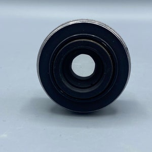 Pu&ograve; includere: Primo piano di un obiettivo per fotocamera nero con un bordo argentato.