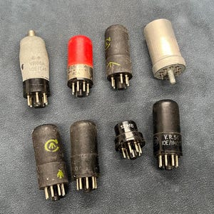 Könnte beinhalten: Eine Sammlung von Vintage-Vakuumröhren in verschiedenen Formen und Größen. Die Röhren sind hauptsächlich schwarz und silber, einige haben rote oder weiße Akzente. Einige Röhren haben aufgedruckten Text, einschließlich Modellnummern.