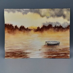 May include: A watercolor painting of a small boat on a lake with a foggy, golden sunset in the background.