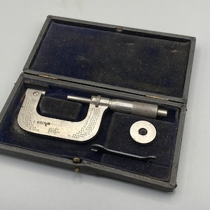 Könnte beinhalten: Ein silberner Mikrometer mit einem schwarzen Etui und einer kleinen silbernen Scheibe. Der Mikrometer ist mit "S. BROWN" und "PERFECTA" sowie einer Seriennummer beschriftet.