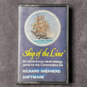 Puede incluir: Cartucho de juego Commodore 64 vintage de "Ship of the Line". La portada presenta una ilustración de un velero dentro de un círculo, sobre un fondo azul oscuro. El título está en escritura amarilla, con detalles del juego e información del editor debajo.