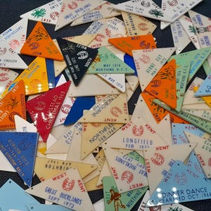 Peut inclure: Un ensemble de fanions triangulaires vintage de différentes couleurs, dont orange, bleu et blanc. Chaque fanion comporte du texte et des graphiques, avec des dates et des lieux tels que "Great Bucklands Sept 1972" et "Dinner Dance Bearsted Oct 1968".