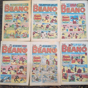 Peut inclure: Six bandes dessinées Beano vintage disposées sur deux rangées. Chaque couverture présente le titre Beano en grandes lettres rouges, avec des vignettes colorées mettant en scène Dennis the Menace et Gnasher. Les couvertures incluent divers titres.