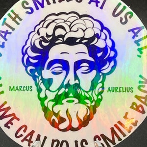 May include: A round, iridescent sticker with a quote from Marcus Aurelius. The sticker features a black and white illustration of a man with a beard and the text "Death smiles at us all; all we can do is smile back".