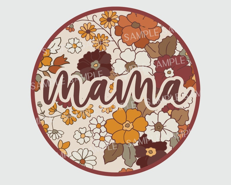 May include: A round, cream-colored background with a floral pattern in shades of orange, brown, and white. The word "mama" is written in a brown cursive font in the center of the circle.