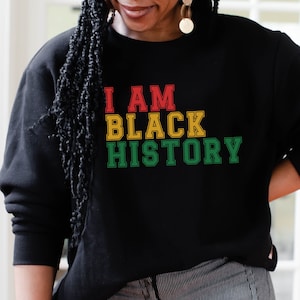 May include: Black sweatshirt with the text "I AM BLACK HISTORY" in red, yellow, and green.