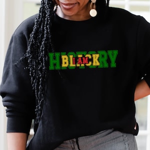 以下が含まれることがあります： 緑、黄色、赤の文字で「History I Am Blackry」と書かれた黒いスウェットシャツ