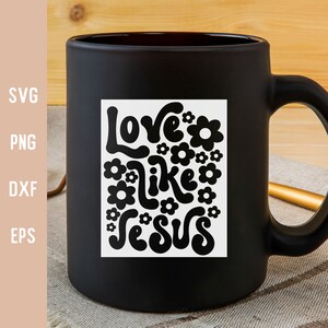 K&ouml;nnte beinhalten: Schwarze Kaffeetasse mit einem wei&szlig;en quadratischen Design mit dem Text "Love like Jesus" in einer Retro-Schriftart mit Blumen, die den Text umgeben.