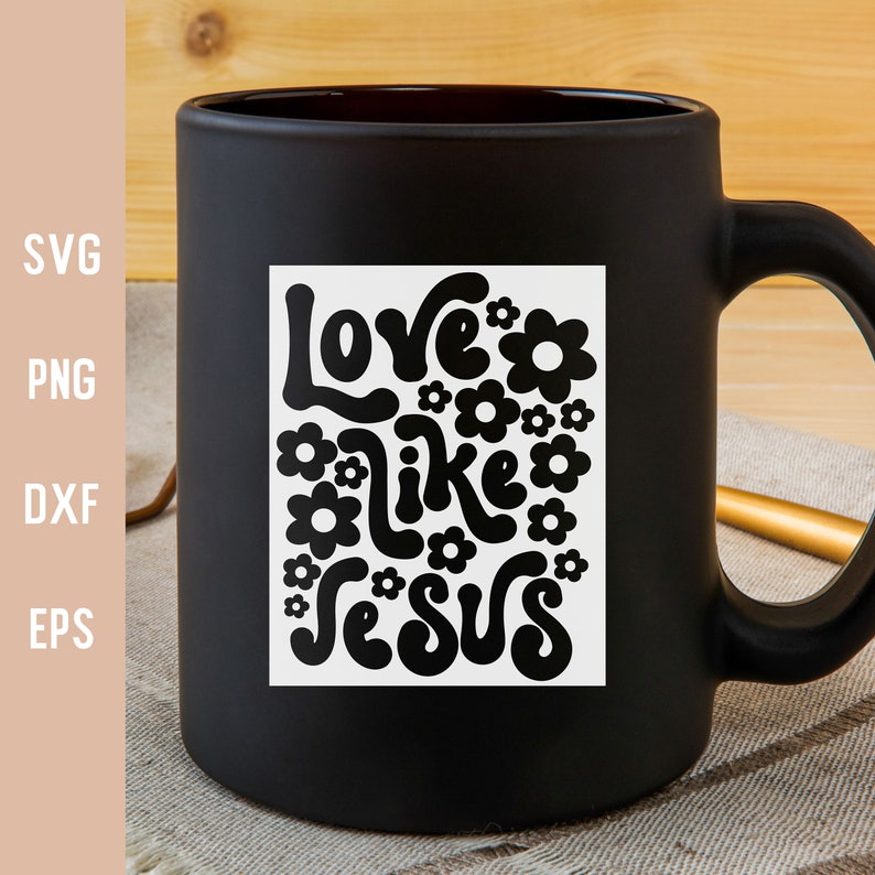 K&ouml;nnte beinhalten: Schwarze Kaffeetasse mit einem wei&szlig;en quadratischen Design mit dem Text "Love like Jesus" in einer Retro-Schriftart mit Blumen, die den Text umgeben.