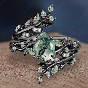 May include: A black ring with a green moss agate stone and a delicate branch design with small clear stones.