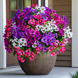 May include: A brown pot filled with a variety of colorful flowers. The flowers are pink, purple, and white. The pot is sitting on a porch.