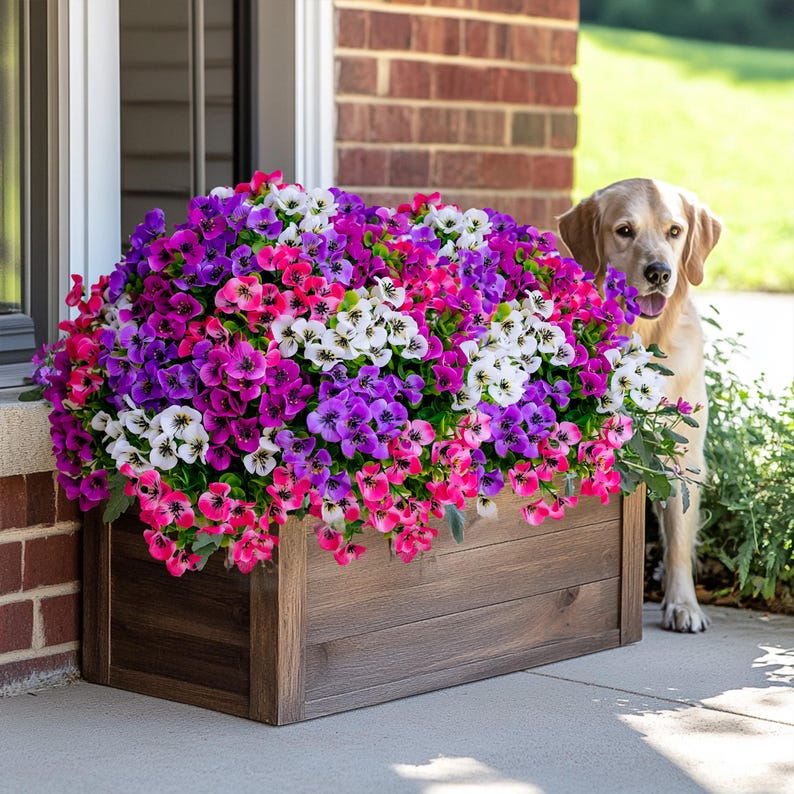 May include: A wooden planter box filled with a variety of colorful flowers, including pink, purple, and white. A dog is standing behind the planter, looking at the flowers.