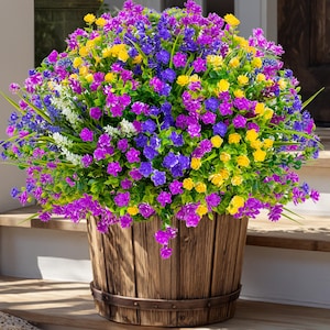 May include: A wooden barrel planter overflowing with vibrant, colorful faux flowers. The arrangement features a mix of purple, yellow, blue, and white blossoms, creating a lively and eye-catching display. The barrel has metal bands and sits on wooden steps.