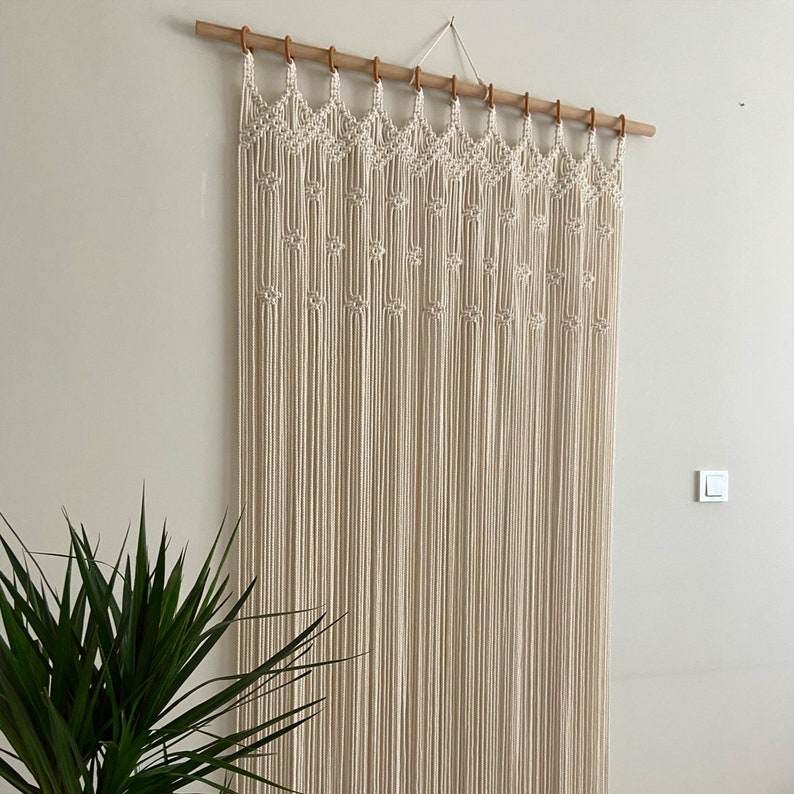 May include: A macrame wall hanging with a geometric pattern, made with natural cotton cord and a wooden dowel rod.