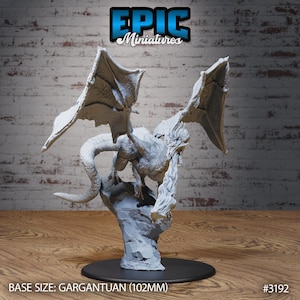 May include: A gray miniature dragon figurine with outstretched wings, perched atop a rocky base. The dragon has detailed scales and a menacing expression. The base size is Gargantuan (102mm). The Epic Miniatures logo is visible.