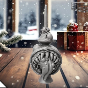 May include: A grey 3D printed Christmas tree ornament shaped like a monster with a large mouth, sharp teeth, and a long, pointed horn on top.