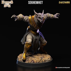 Könnte beinhalten: Eine bemalte Miniaturfigur von Sekhmet, einer ägyptischen Göttin, die als Löwin dargestellt wird, trägt ein weißes Leinengewand und goldenen Schmuck. Die Figur ist in einer dynamischen Pose mit offenem Mund und scharfen Zähnen dargestellt. Die Figur ist vor einem schwarzen Hintergrund platziert.