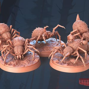 Peut inclure: Quatre figurines de araignées brunes détaillées sur des socles ronds. Les araignées ont des corps velus et de longues pattes. STL Miniatures est imprimé dans le coin supérieur gauche de l'image.