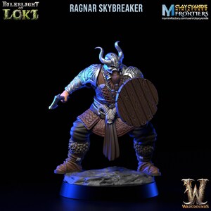 Puede incluir: Una figura miniatura pintada de un guerrero con un escudo y un hacha. La figura lleva un casco con cuernos, una túnica de cuero marrón y una capa de piel. La figura está de pie sobre una base rocosa. La figura está pintada en una variedad de colores, incluyendo plata, marrón y rojo. La figura es del juego "Bileblight of Loki".