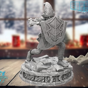 Op de afbeelding: Een grijze figuur van een fantasiekarakter in een dynamische pose, met een schild en wapen. De figuur staat op een gedetailleerde basis. De achtergrond is wazig, wat wijst op een winterse scène. De figuur heeft de tekst "Witchsong" op de basis.