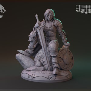 Op de afbeelding: Een grijs 3D-geprint miniatuur van een vrouwelijke krijger in harnas, met een zwaard en schild, zittend op een rots.
